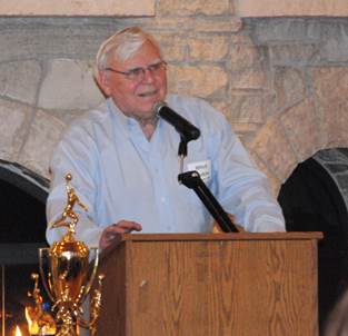 Former Rend Lake College Coach Mitch Haskins stood next to the National Championship trophy Saturday night to speak during the Men's Basketball Alumni Dinner, held at the Rend Lake Resort. Haskins was the head coach for the team from 1981 until 1992. (ReAnne Palmer / RLC Public Information